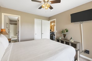 A hotel room with a large bed, a ceiling fan, a flat-screen TV, and a bedside table with a lamp. - Serene Two-Bedroom Condo with Pond View near Branson Shows & Attractions (Branson)