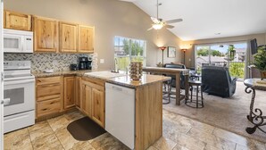 A kitchen with wooden cabinets, a dishwasher, and a dining area with a ceiling fan.