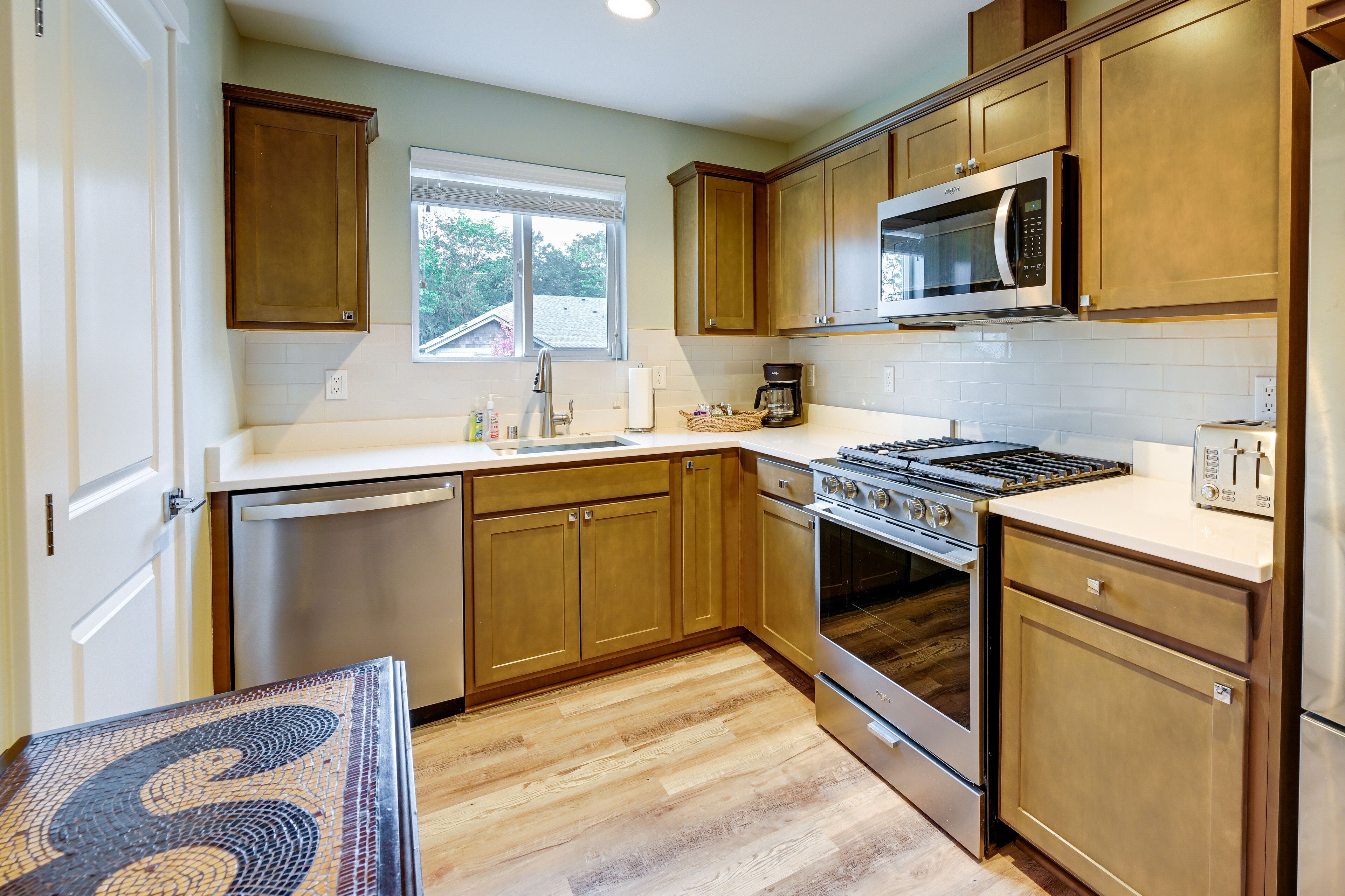 A kitchen with wooden cabinets, a stainless steel stove, a microwave, and a dishwasher.