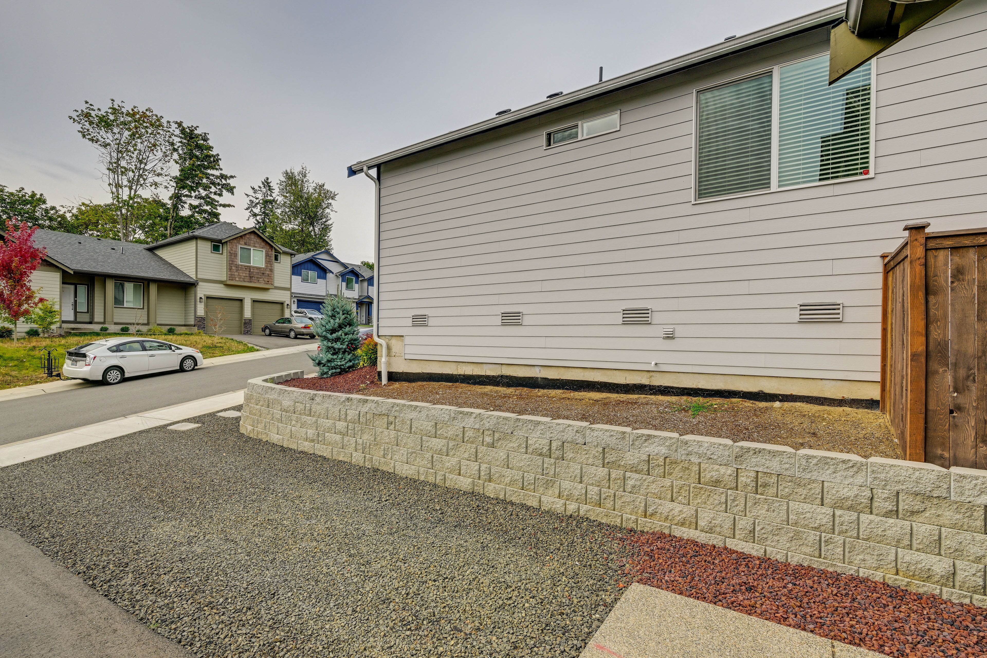 A residential building with a garage, a driveway, and a small garden area with a brick border and gravel.