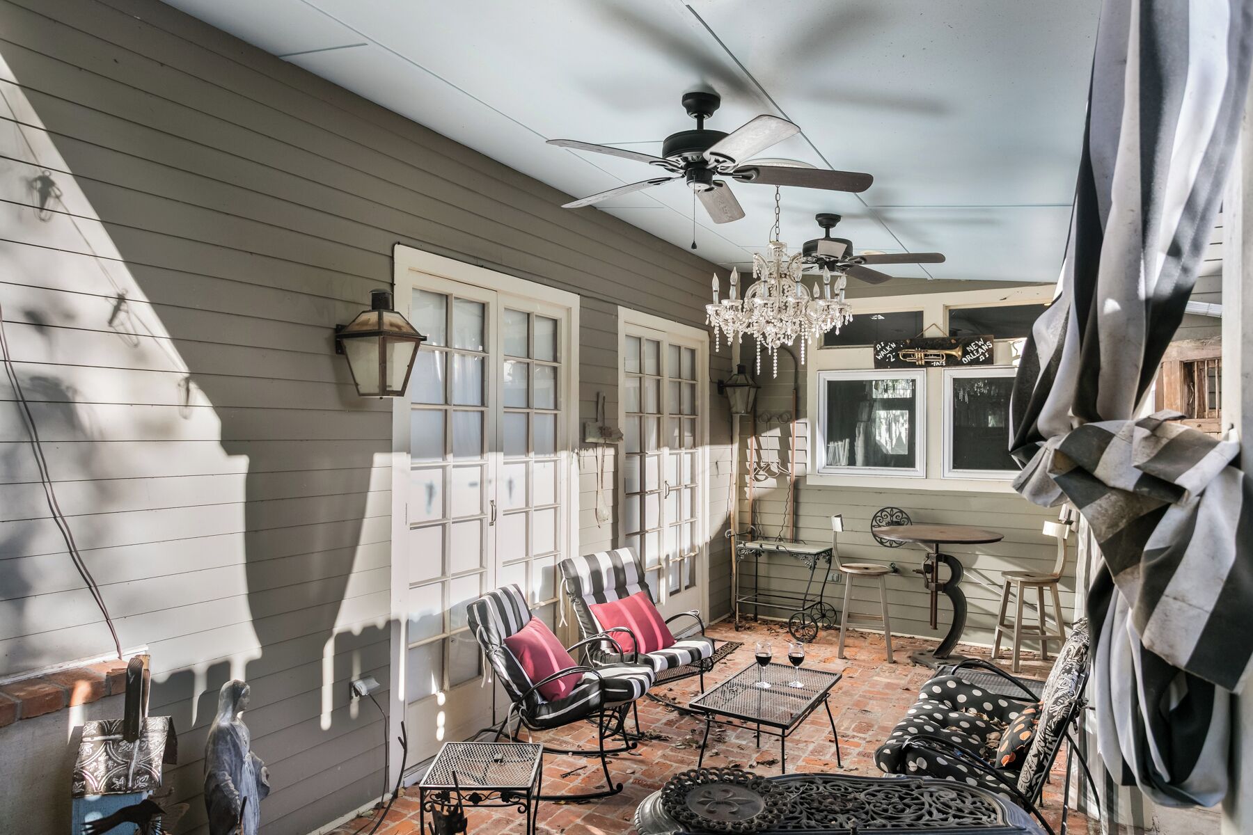 A covered patio with a ceiling fan, outdoor seating, and a chandelier.