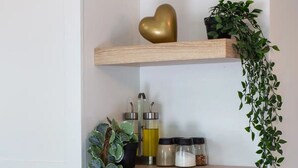 Una cocina con estantes de madera, un bloque de cuchillos y una planta en maceta.