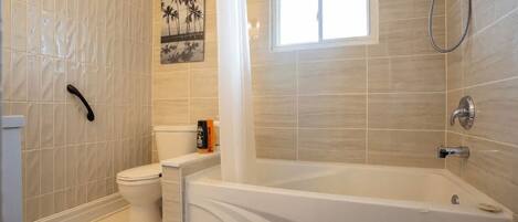 A bathroom with a bathtub, toilet, and shower.