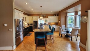 Una cocina amplia con una isla central, suelo de madera y armarios blancos.