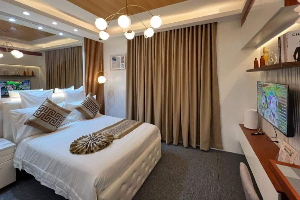 Une chambre d’hôtel moderne équipée d’un grand lit, d’une télévision et d’un bureau avec une chaise.