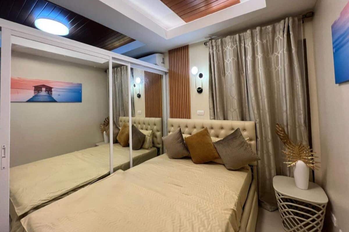 Une chambre à coucher avec un grand lit, un miroir, une table de chevet et un tableau accroché au mur.
