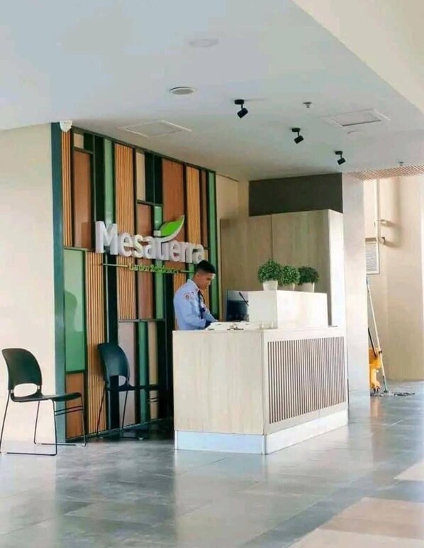 A reception area with a modern design, featuring a reception desk, a receptionist, and a potted plant. - Rinann's Mesatierra Garden Residences (Davao)