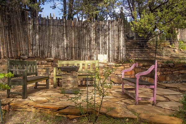 A patio area with stone flooring, wooden benches, and a stone wall.