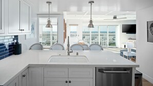 Een moderne keuken met witte kasten, een RVS vaatwasser en een groot kookeiland met een spoelbak.