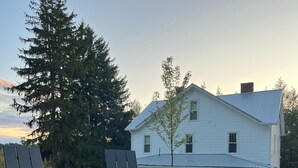 A white house with a chimney, surrounded by a gravel area with two Adirondack chairs. - Private Vacation Home with large Hot Tub and Fire Pit -- Sleeps 18 (Gibsonia)
