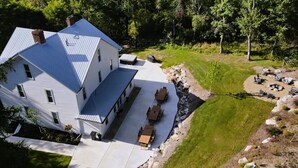 A large, modern house with a spacious patio area, a well-maintained lawn, and a fire pit setup. - Private Vacation Home with large Hot Tub and Fire Pit -- Sleeps 18 (Gibsonia)