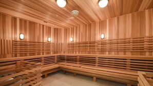 A sauna with wooden benches and slatted walls, equipped with ceiling lights.