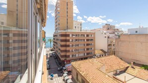 A multi-story building with a mix of residential and commercial spaces, featuring a street with parked cars and a visible storefront. - Beach front apartment in Torrevieja with WiFi (Torrevieja)