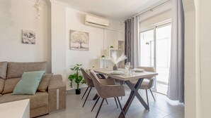 A modern living room with a sofa, dining table, chairs, and a potted plant. - Beach front apartment in Torrevieja with WiFi (Torrevieja)