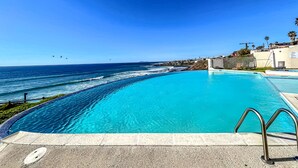 Une piscine d’un bleu éclatant, avec vue sur l’océan et une côte lointaine.