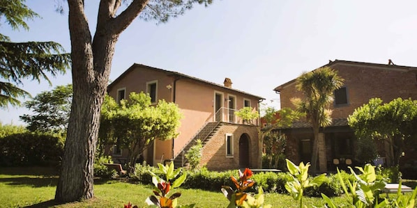 A building with a brick facade, a central staircase, and a garden with various plants.