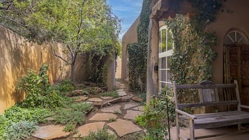 Un sendero en el jardín con escalones de piedra que llevan a un banco de madera.