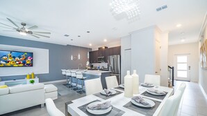 Une cuisine moderne avec un coin repas, des meubles blancs et un ventilateur de plafond.