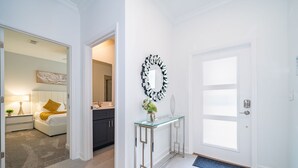Un intérieur moderne avec une console en verre, un miroir décoratif et une porte blanche.