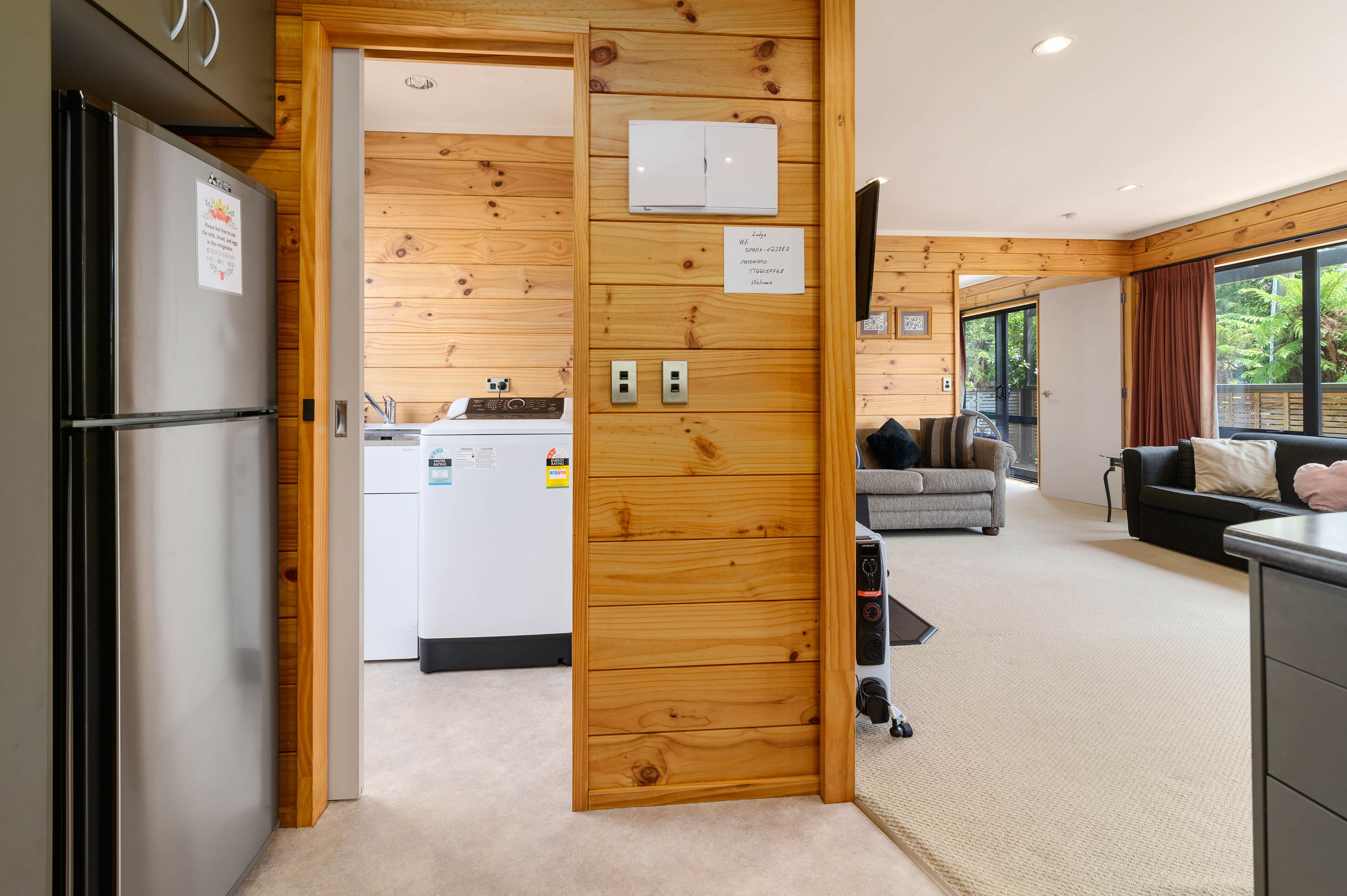 Eine moderne Küche mit integriertem Kühlschrank, Holzvertäfelung und einem Essbereich inklusive Sofa und Tisch.