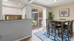 A kitchen with white cabinets, a stone backsplash, and a dining area with a table and chairs. - 5 STAR Townhome near all major highways! Fast Wifi (Carrollton)