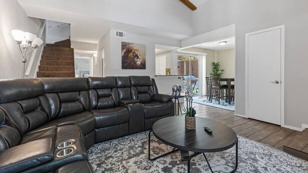 A spacious living room with a leather sectional sofa, a round coffee table, and a patterned rug. - 5 STAR Townhome near all major highways! Fast Wifi (Carrollton)