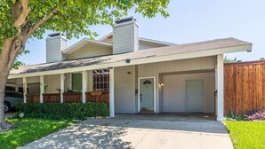 A two-story house with a covered porch, a garage, and a fenced backyard. - 5 STAR Townhome near all major highways! Fast Wifi (Carrollton)