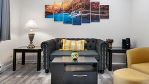 Un salon comprenant un canapé, une table basse, une table d’appoint avec une lampe et une œuvre d’art accrochée au mur.