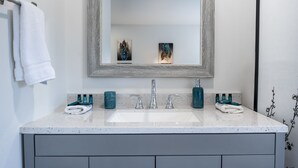 Une salle de bain moderne avec un grand miroir, deux lavabos et un meuble-lavabo doté de tiroirs.