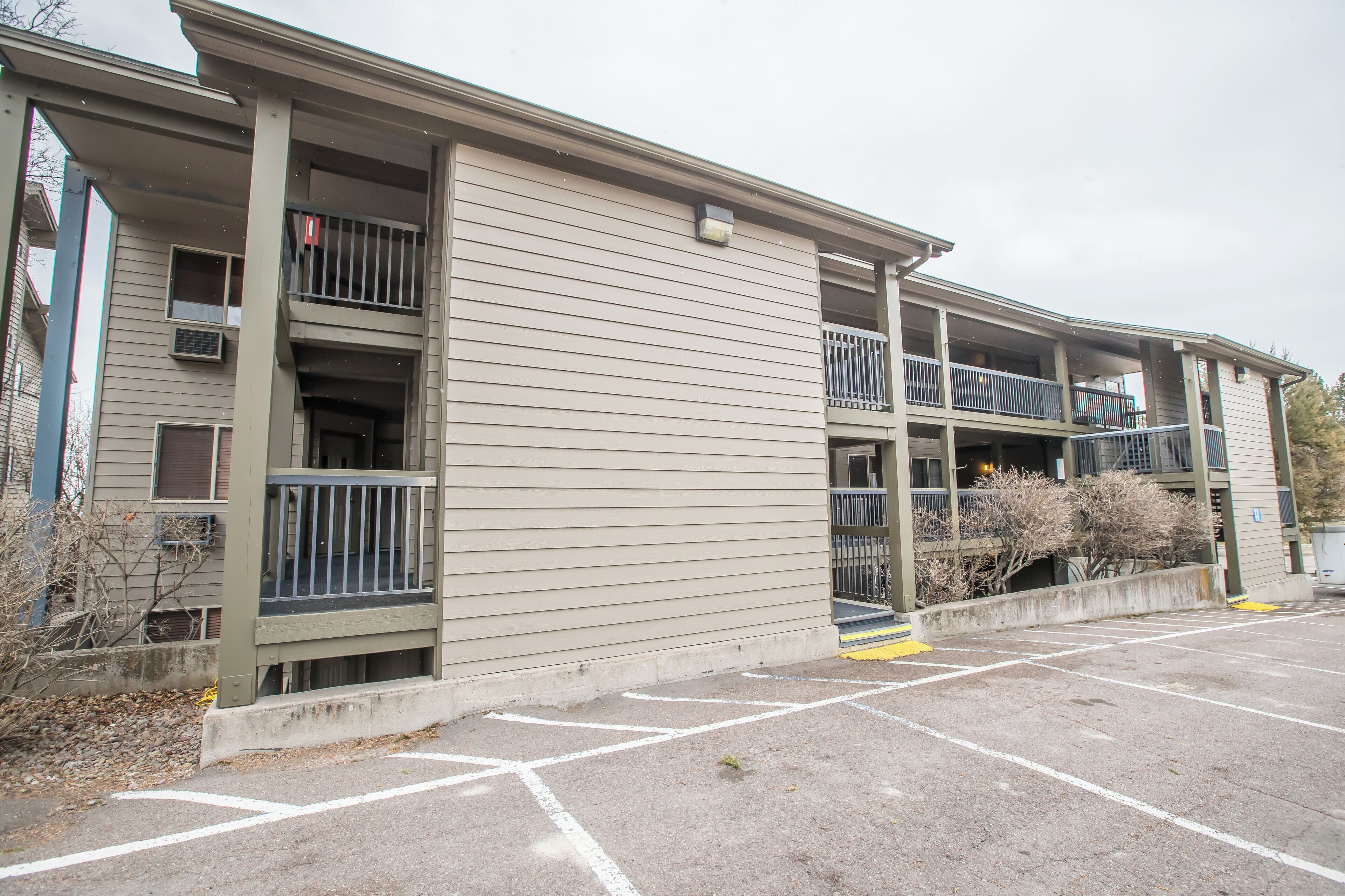 A multi-story building with balconies and a parking lot.