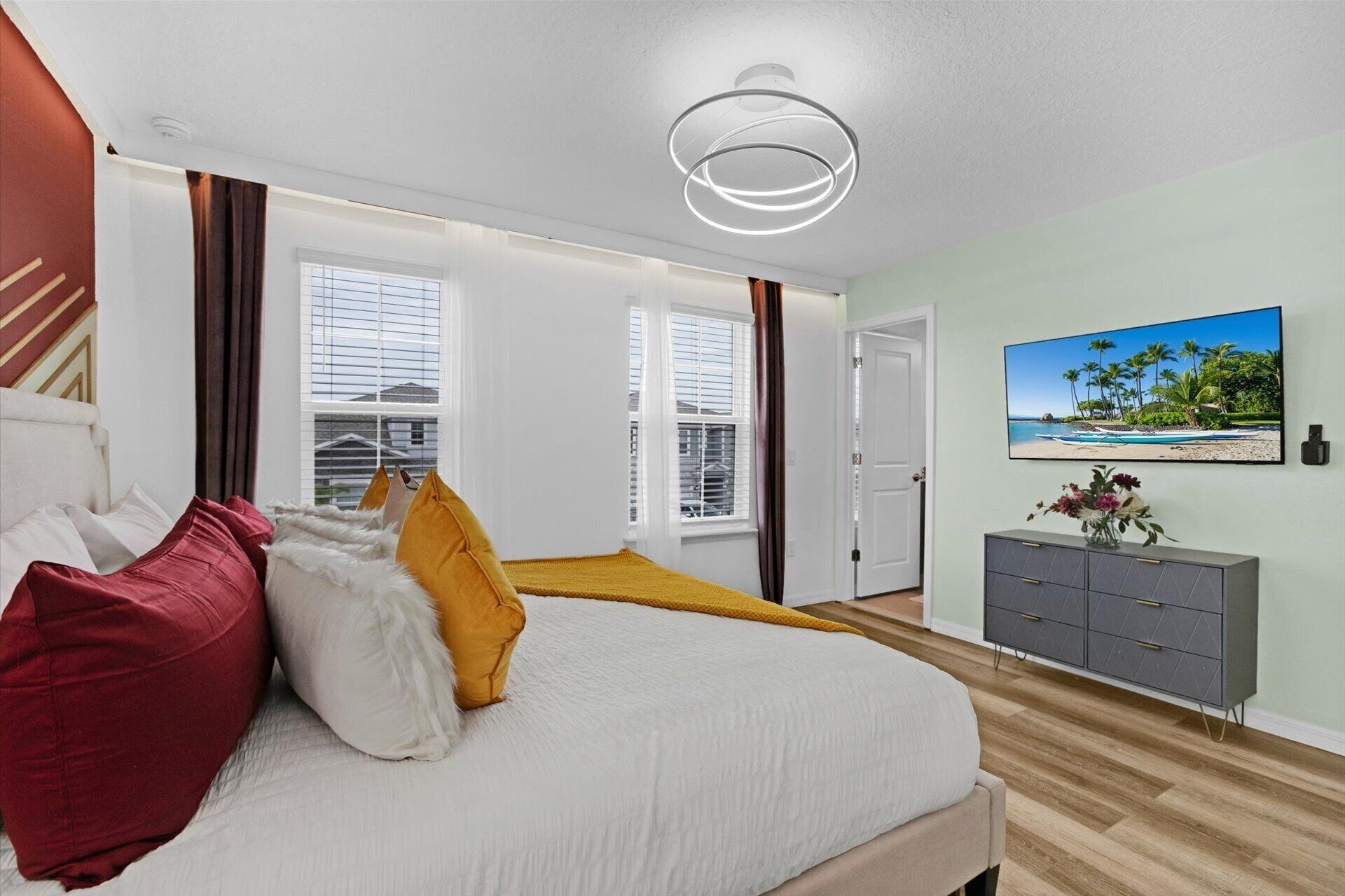 Une chambre à coucher avec un lit, une table de chevet, une télévision et une fenêtre avec des stores.
