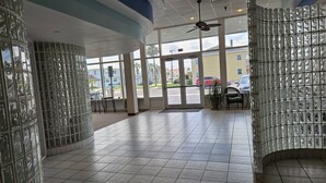 A spacious lobby with a tiled floor, large windows, and a ceiling fan.