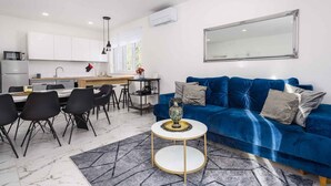 A modern living room with a blue sofa, a round coffee table, and a dining area with a white table and black chairs. - Villa with pool, air conditioning, internet and covered terrace, near the sea (Umag)
