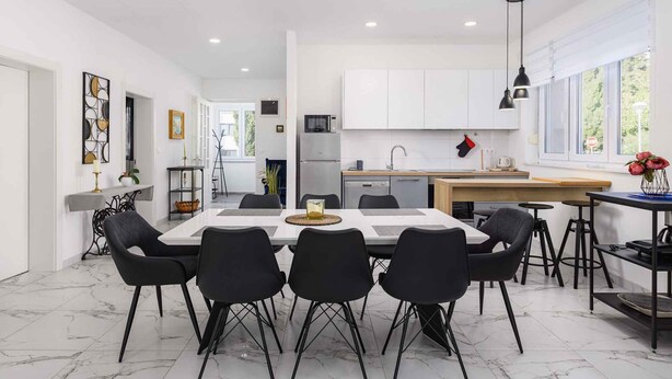 A modern kitchen with white cabinets, a dining area with a marble floor, and a large window providing natural light. - Villa with pool, air conditioning, internet and covered terrace, near the sea (Umag)