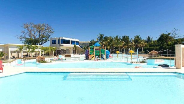 A swimming pool with a water slide and a building in the background. - Villa Royale Luxury 4-bedroom Paradise In Sosua (Sosúa)
