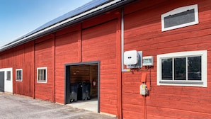 En röd byggnad med en stor, öppen dörr, ett fönster och elcentraler på sidan.