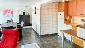 Ett modernt kök med träskåp, ett vitt kylskåp och en kakelbeklädd vägg bakom arbetsbänken.