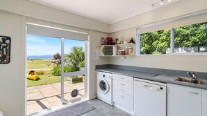 Een moderne keuken met een ingebouwde wasmachine en droger, grote ramen en uitzicht op de omgeving.