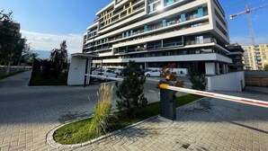 Een modern gebouw met meerdere verdiepingen, een plat dak, grote ramen en een hekwerk.