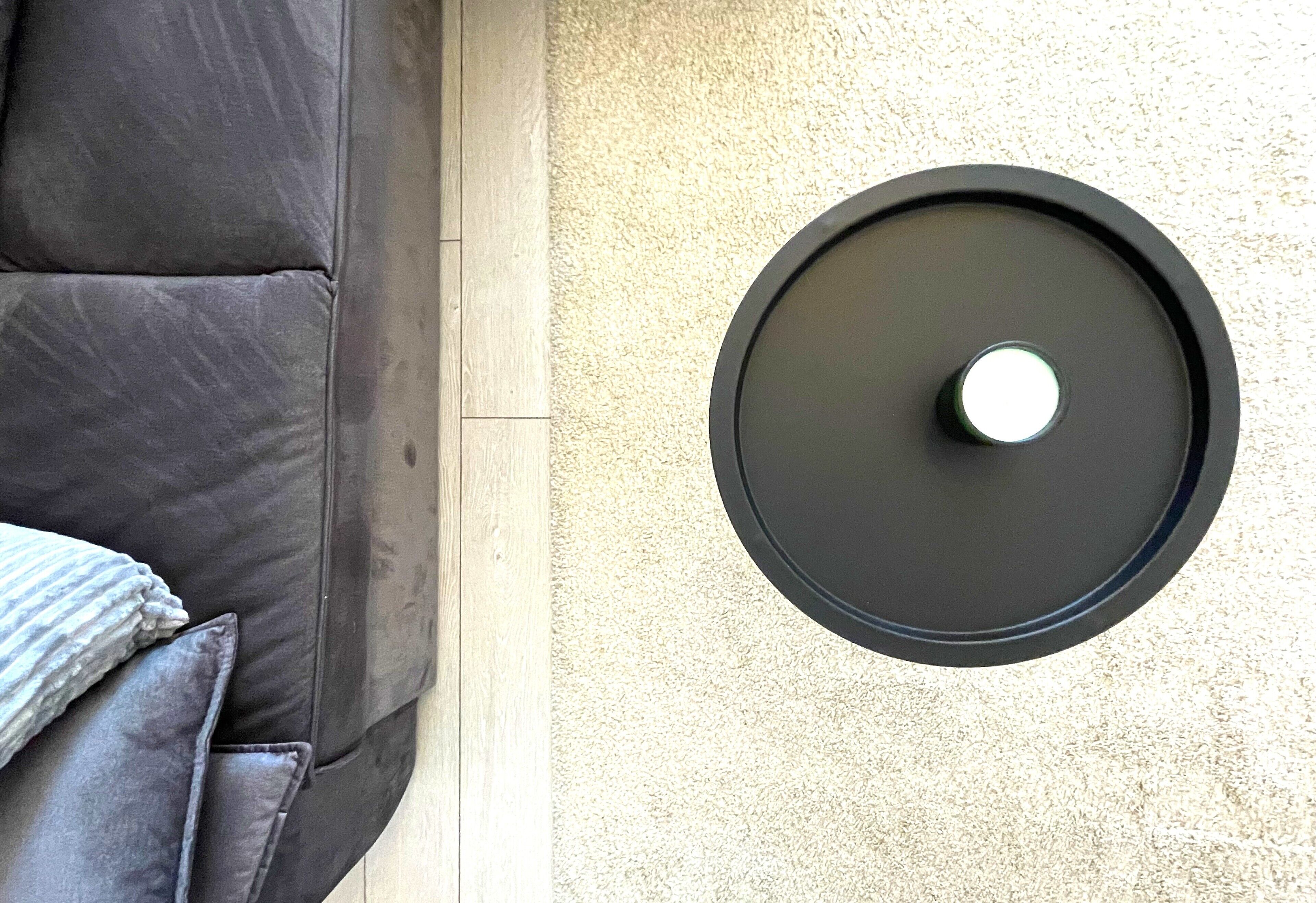 A modern room with a dark-colored sofa, a round black table, and a textured wall.