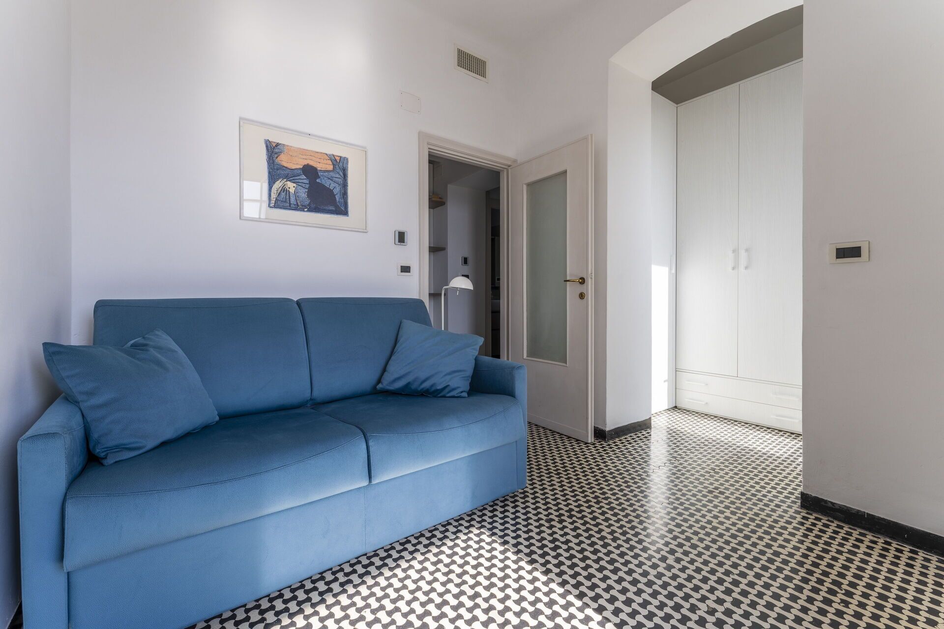 Un salon moderne avec un canapé bleu et un sol à motifs.