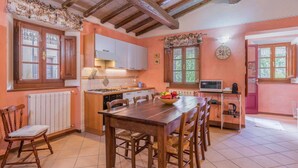 Una cocina con armarios de madera, una estufa y un comedor con mesa y sillas.