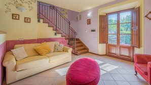Una sala de estar con sofá, reposapiés, escalera y un ventanal con vistas.