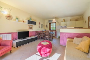 Una sala de estar con televisor, asientos, comedor y cocina.