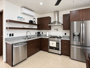 A modern kitchen with stainless steel appliances, a built-in oven, and a refrigerator. - Tropical 2BR Villa with Private Plunge Pool (First Bight)