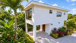 A modern two-story house with a balcony, surrounded by lush tropical vegetation. - Tropical 2BR Villa with Private Plunge Pool (First Bight)