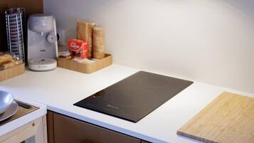 Une cuisine moderne dotée d’une plaque de cuisson à induction intégrée, d’une machine à café et d’une planche à découper en bois.