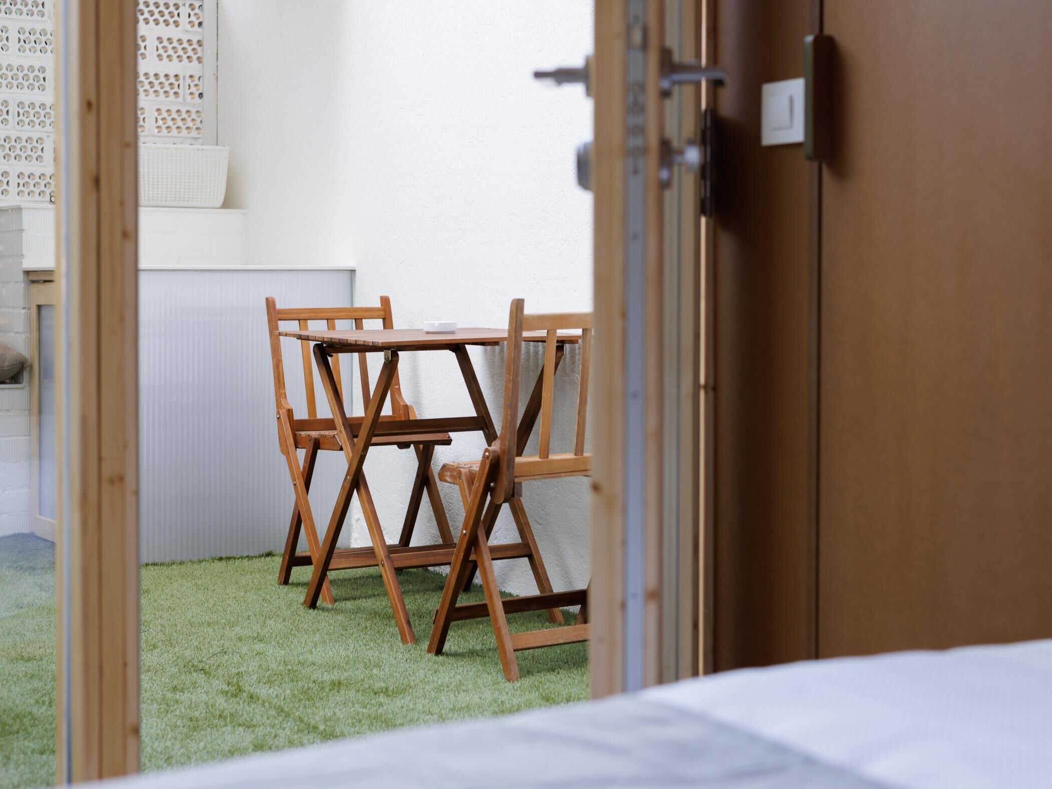 Una habitación con una mesa y sillas de madera, una puerta blanca y vistas a un área con césped.