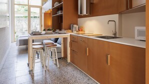 A modern kitchen with wooden cabinets, a stainless steel range hood, and a built-in microwave. - Apartamento estudio con terraza-pensión* (A Estrada)