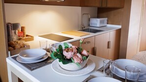 A modern kitchen with a stainless steel range hood, a microwave, and a wooden cutting board on the countertop. - Apartamento estudio con terraza-pensión* (A Estrada)